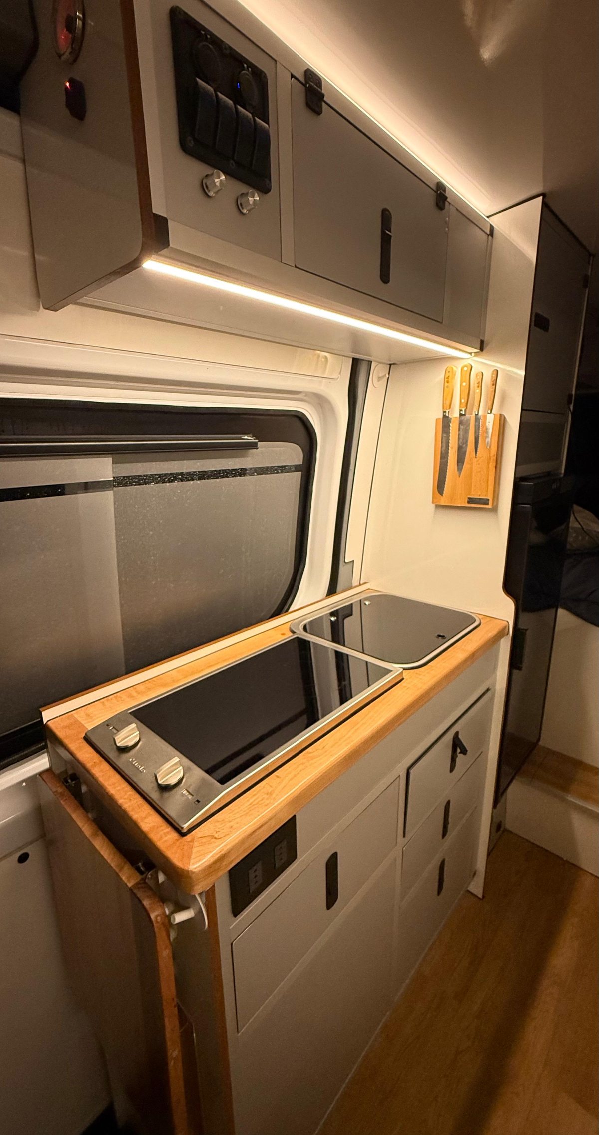 Camper kitchen with induction cooktop, sink and wood countertop