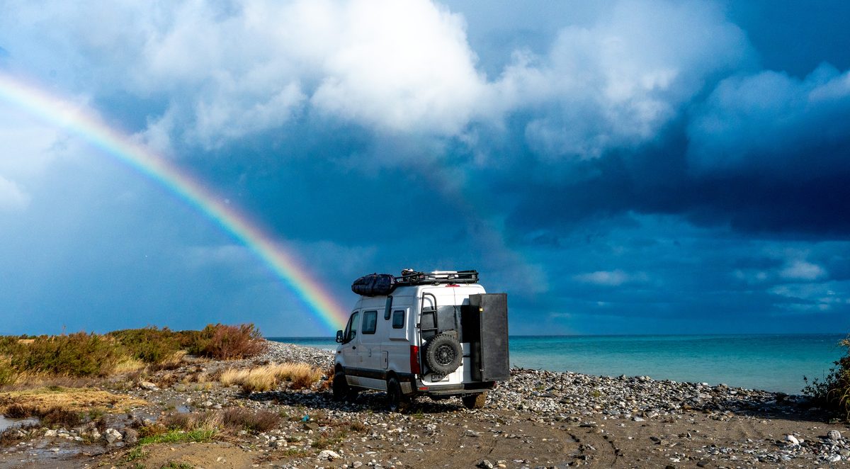 Mercedes Sprinter 4x4 camper parked on the coast under a rainbow