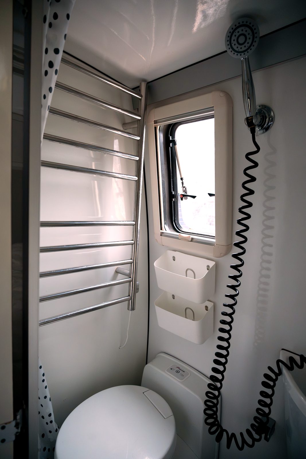 Camper bathroom with towel rack, shower head and toilet