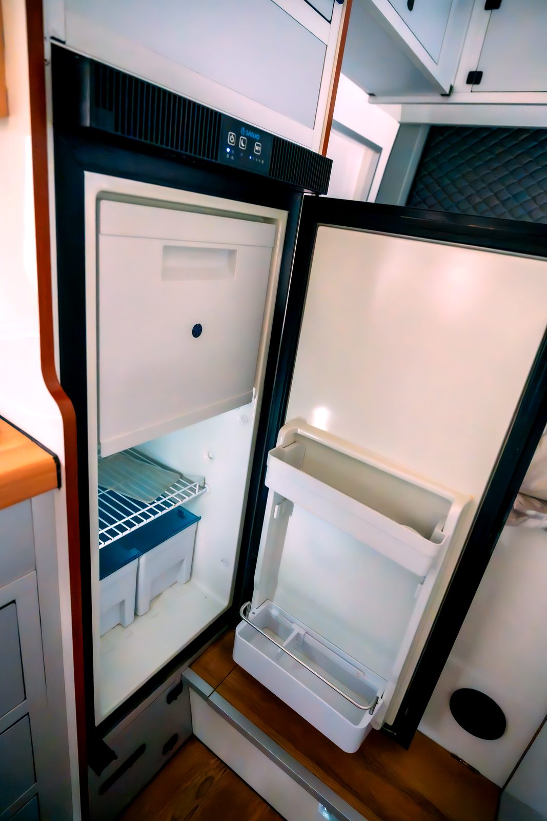 Open 90-liter fridge inside the camper kitchen